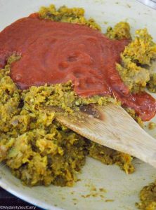 adding tomato puree to curry paste