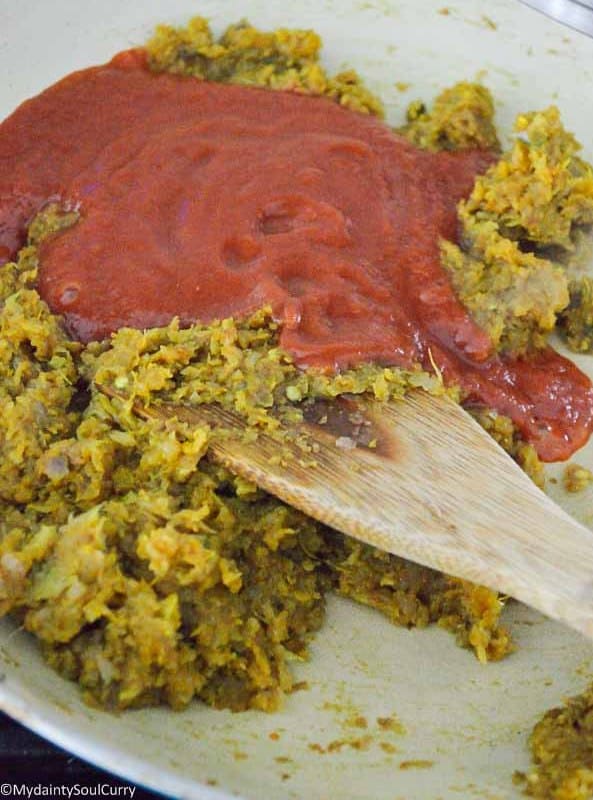 adding tomato puree to curry paste