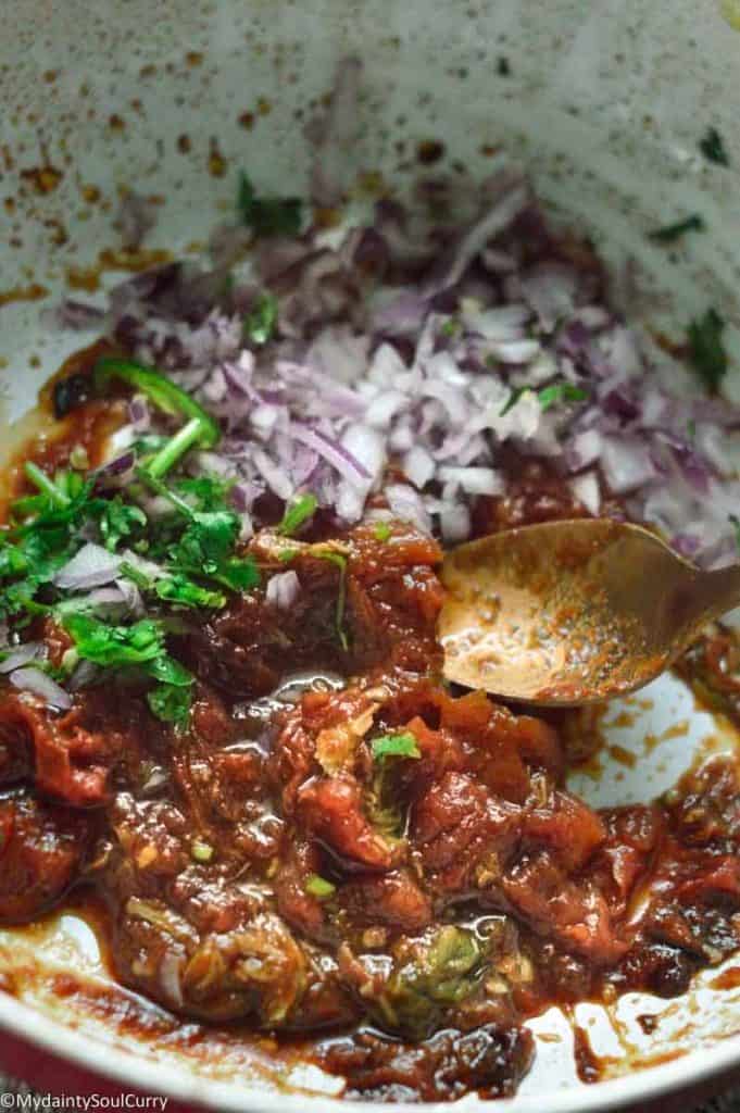 mashing tomatoes for choka