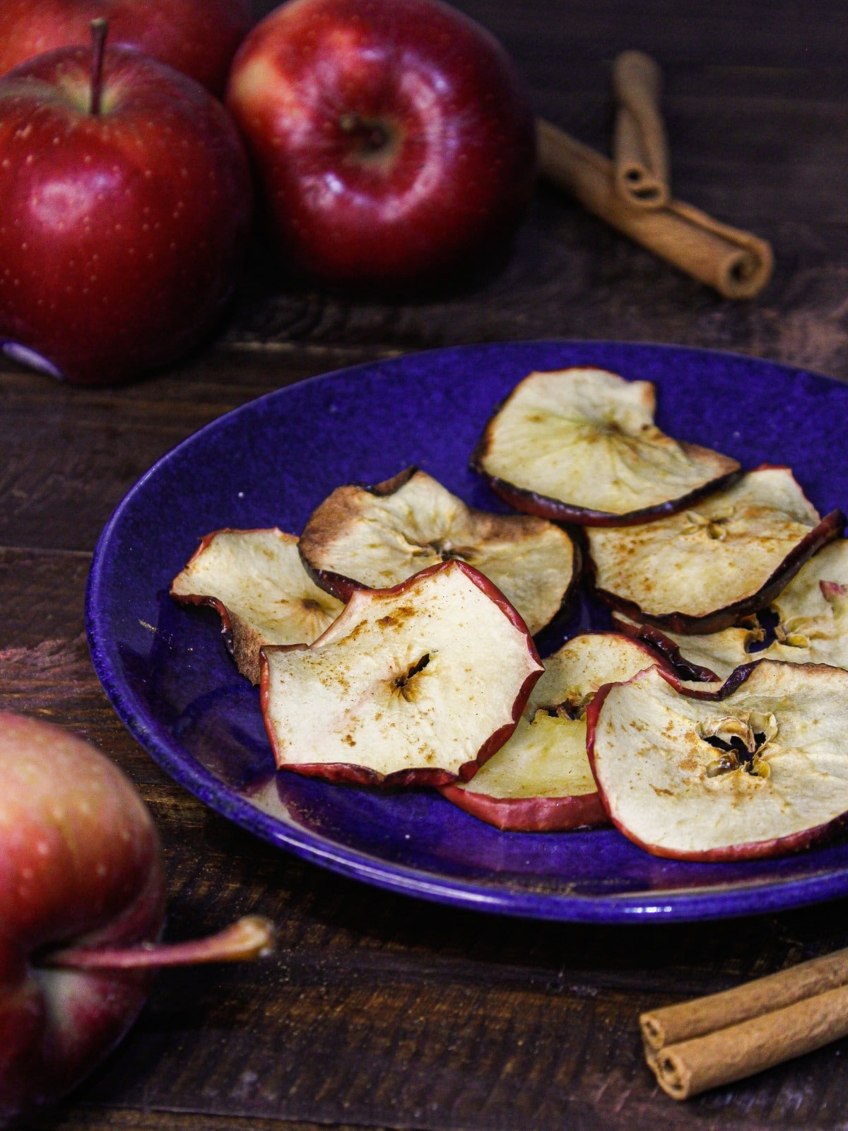 Air Fried Apple Chips on a plate with apples in the background
