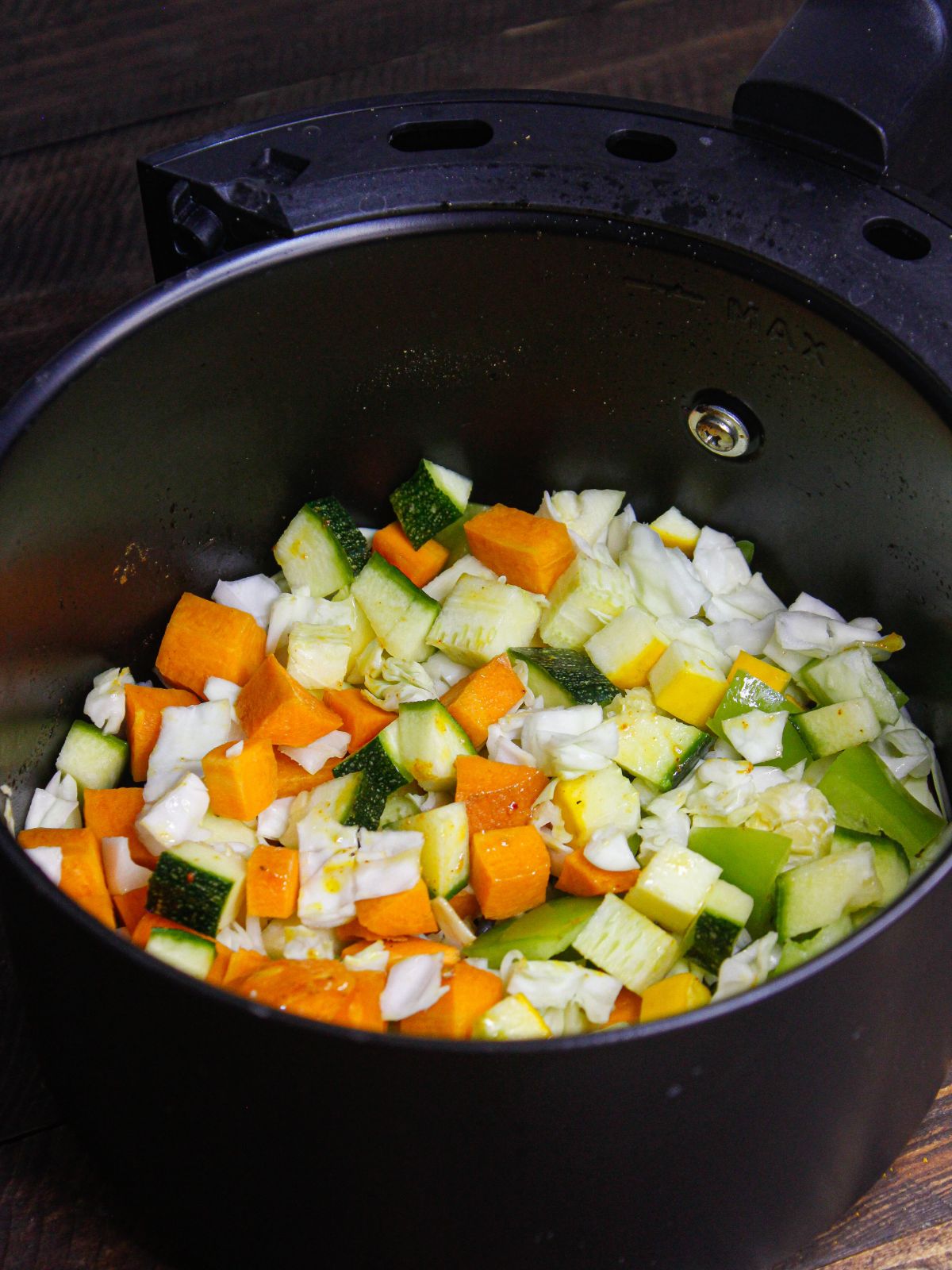 Chopped raw vegetables in a air fryer basket for Vegetable Fried Rice 
