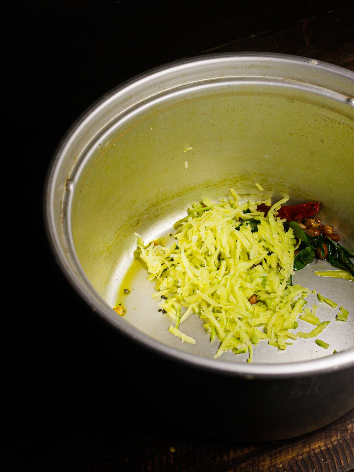 Add grated raw mangoes to the pot and saute well