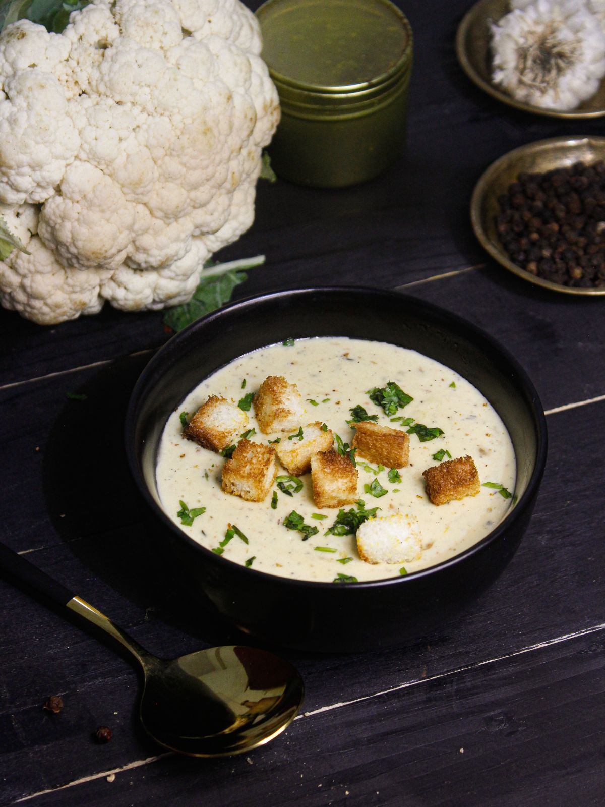 Yummy Instant Pot Creamy Cauliflower Soup served in a bowl with raw cauliflower in the background