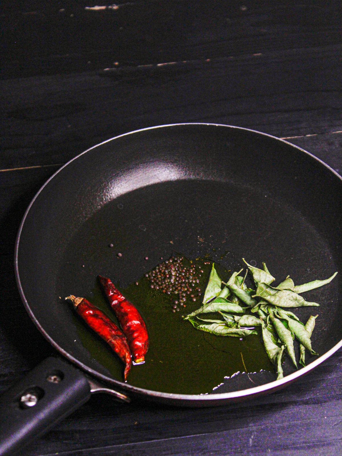 Take oil, curry leaves, red chili and cumin seeds in a pan and saute