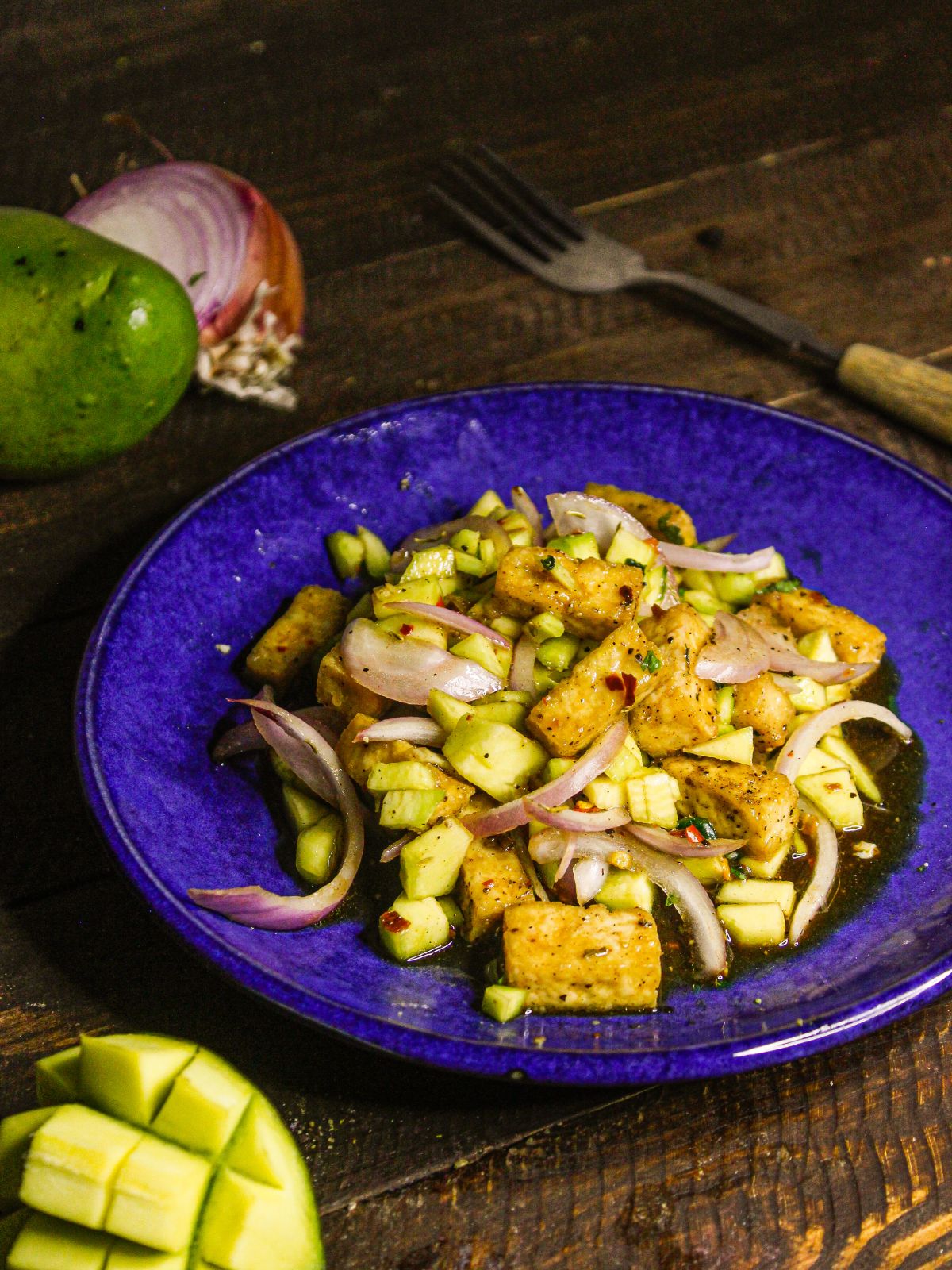 Spicy Raw Mango Tofu Salad with raw mango in the background 