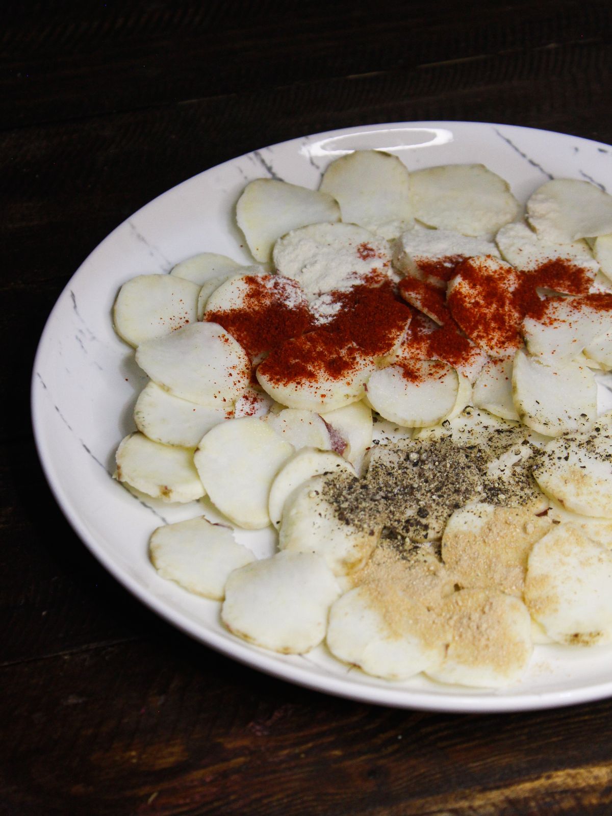 Add all the dried spices over the potato slices