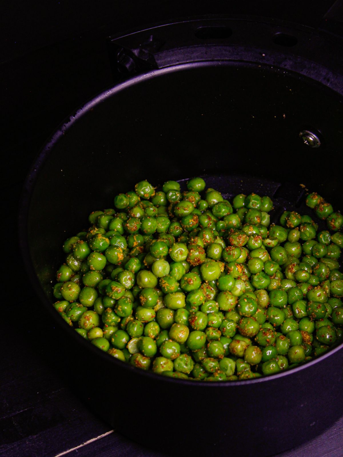 Transfer the peas into the air fryer basket and spray some oil over it 