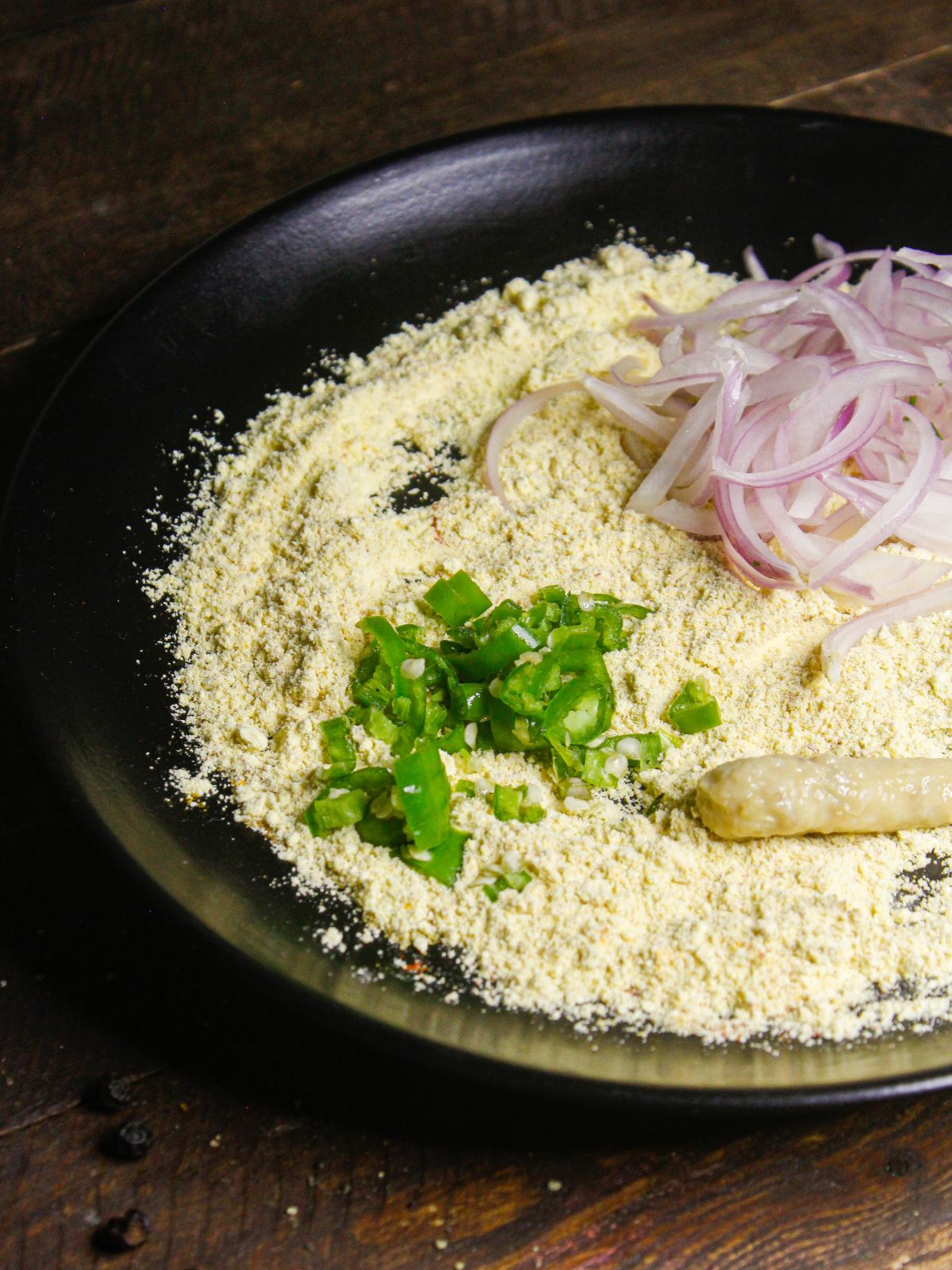 Add sliced onions, chopped green chilies and ginger garlic paste on the besan mixture  