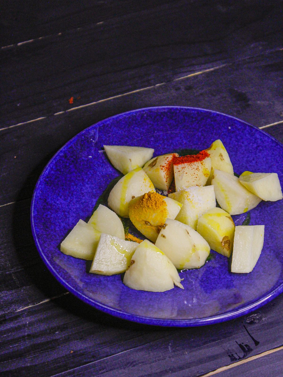Take cubed potatoes on a plate and marinate it with powdered spices 