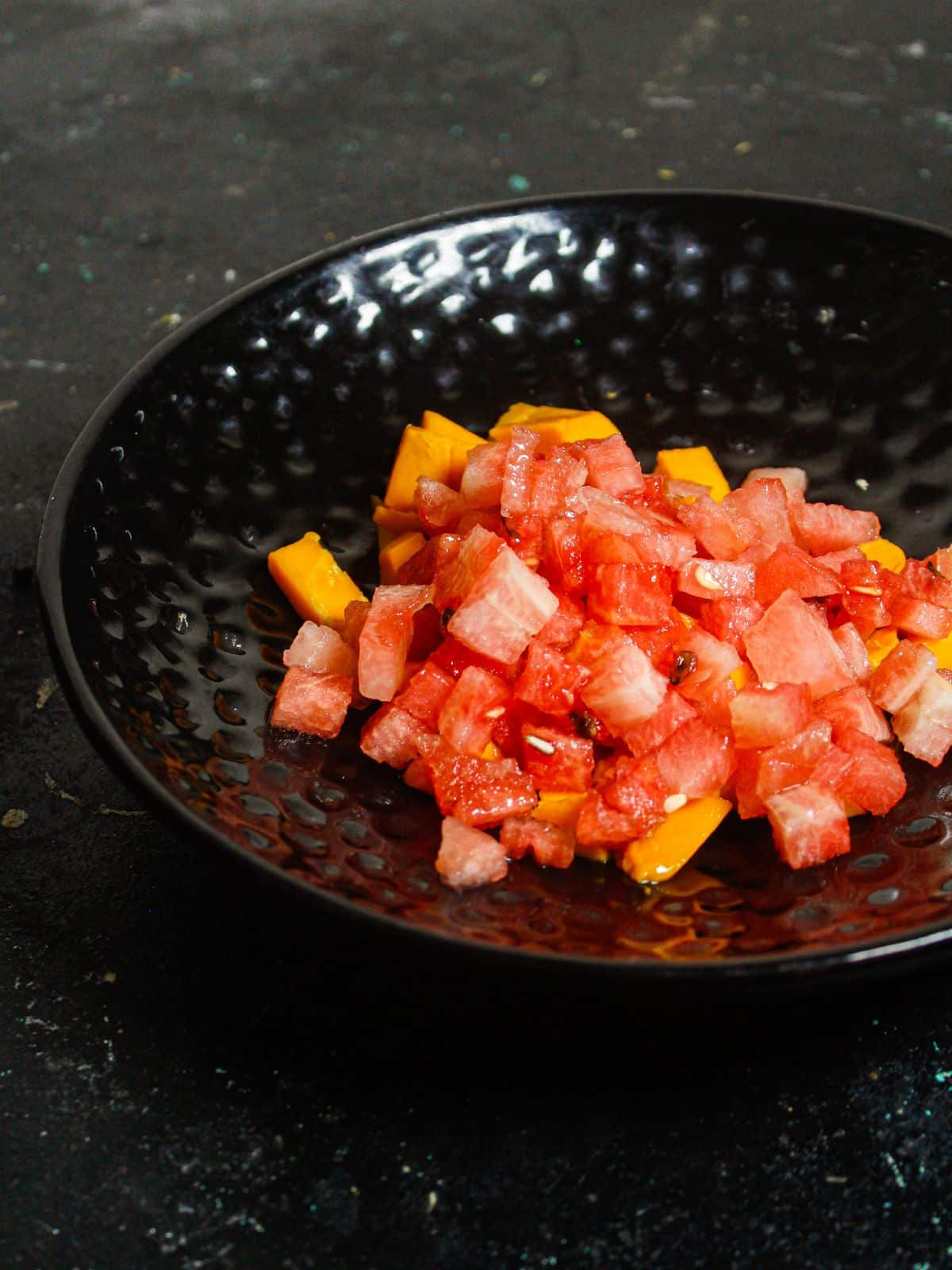 Add pieces of watermelon over the mango in a saucer