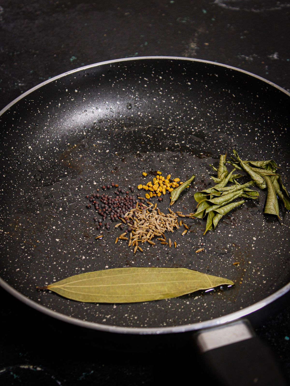 Add oil, mustard seeds, cumin seeds, fenugreek seeds, curry leaves, and bay leaf in a pan and saute 