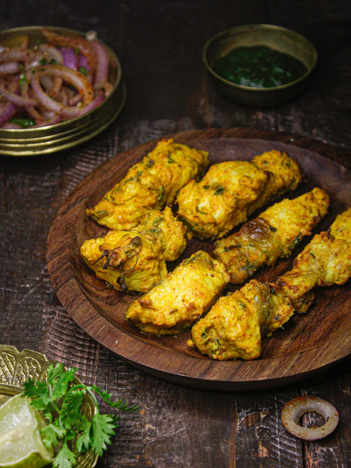 Delicious Air Fried Amritsari Fish served on a wooden platter with Onion Salad and Green Chutney