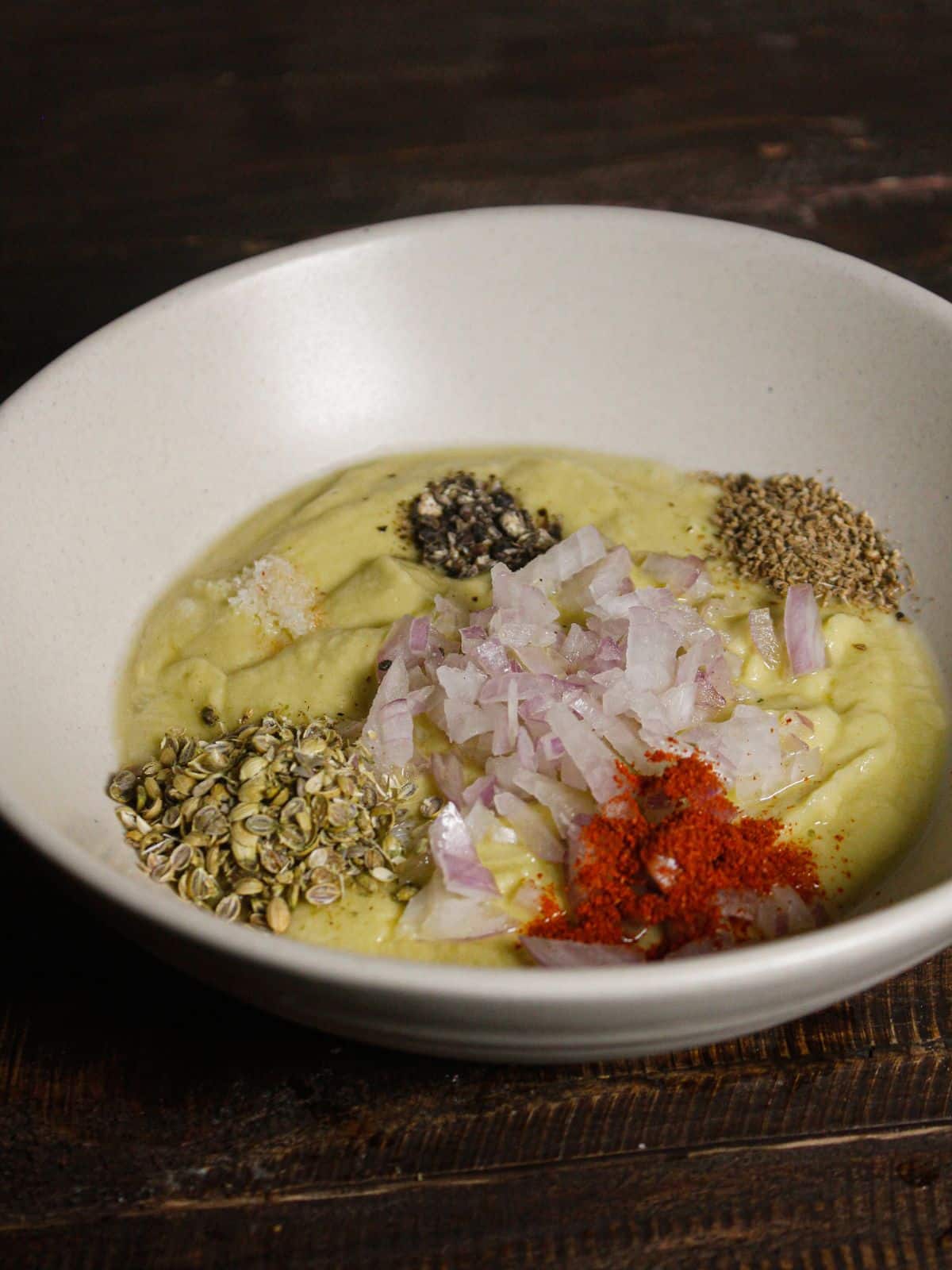 Transfer the paste into the bowl and add chopped onions and powdered spices to the bowl