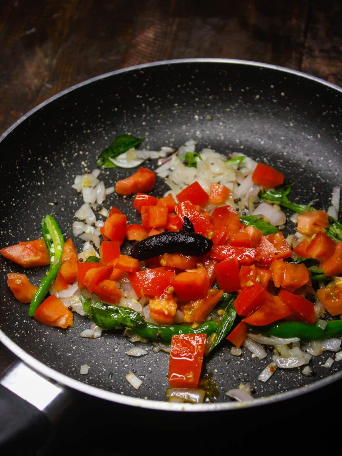 Add chopped tomatoes and tamarind paste into the pan 