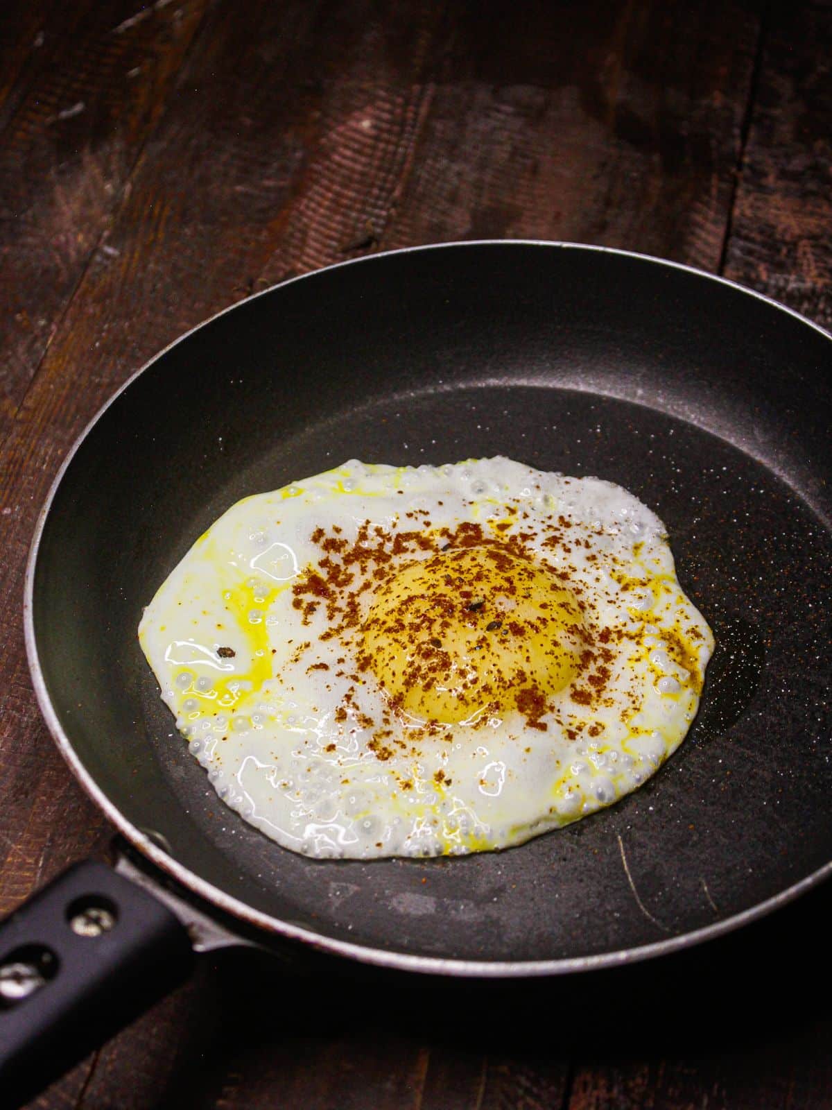 Cook half fry egg in another pan and add paprika powder over it  