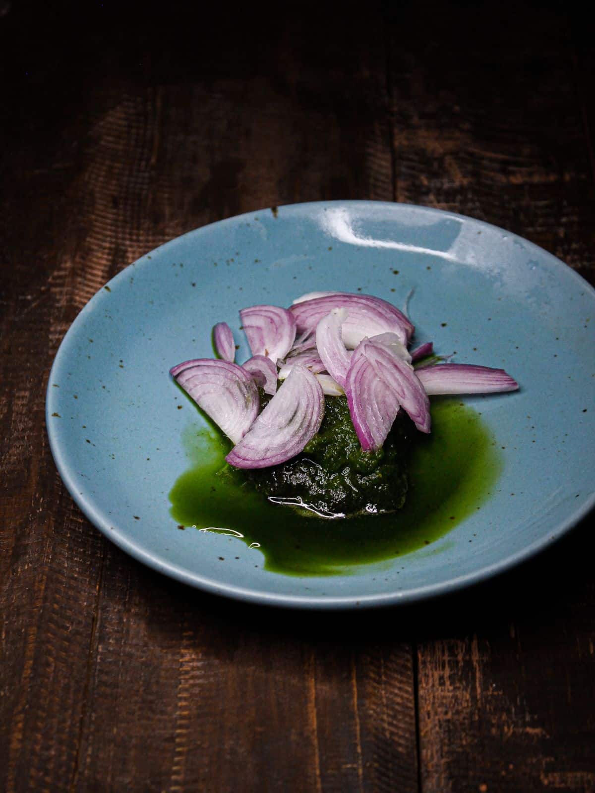 Add sliced onions over the green paste into the pan 