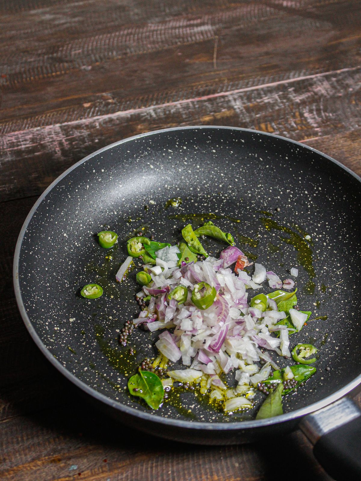 Add chopped onions and green chilies in a pan 