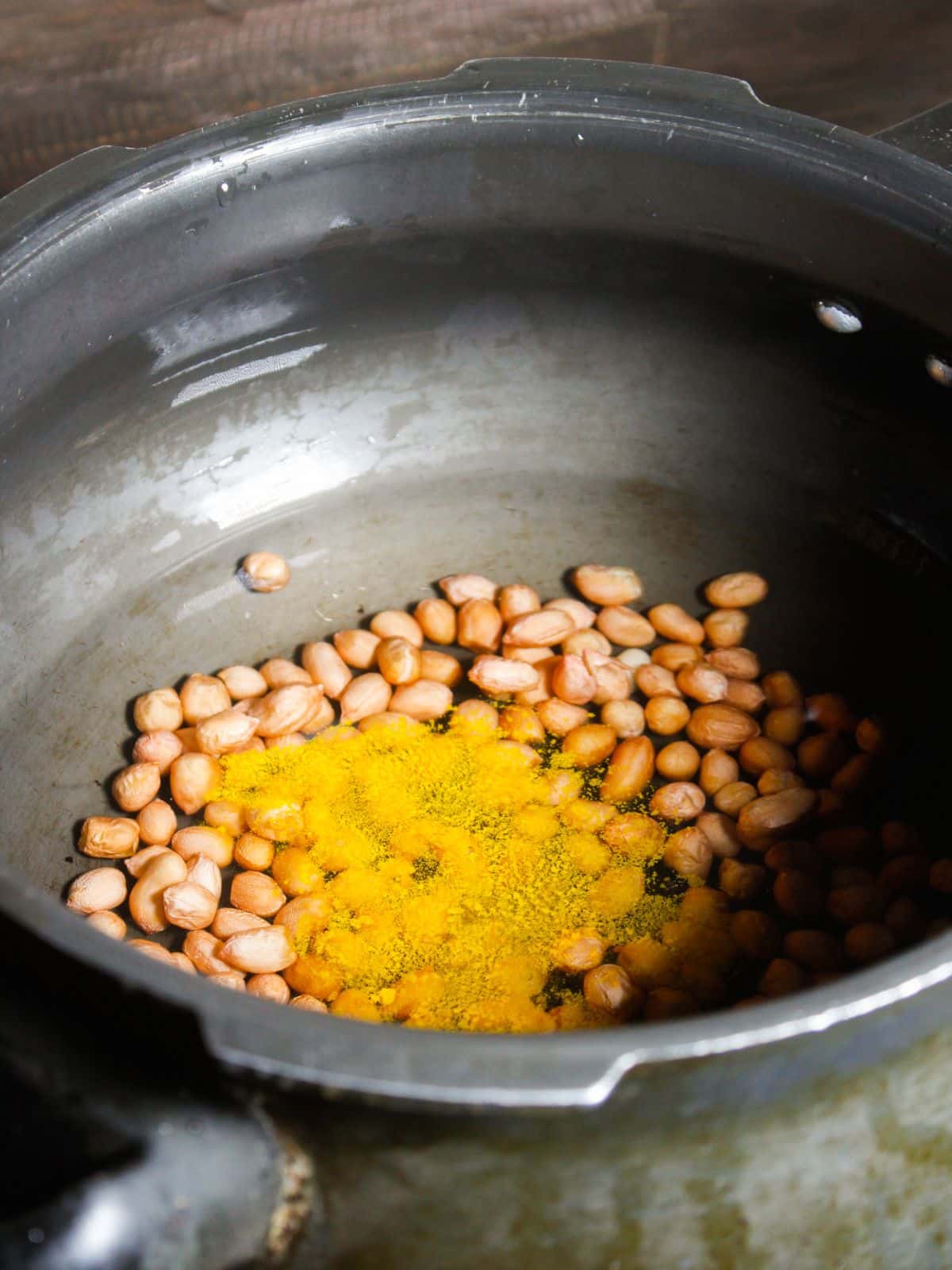 Peanuts, turmeric, salt and water in a cooker 