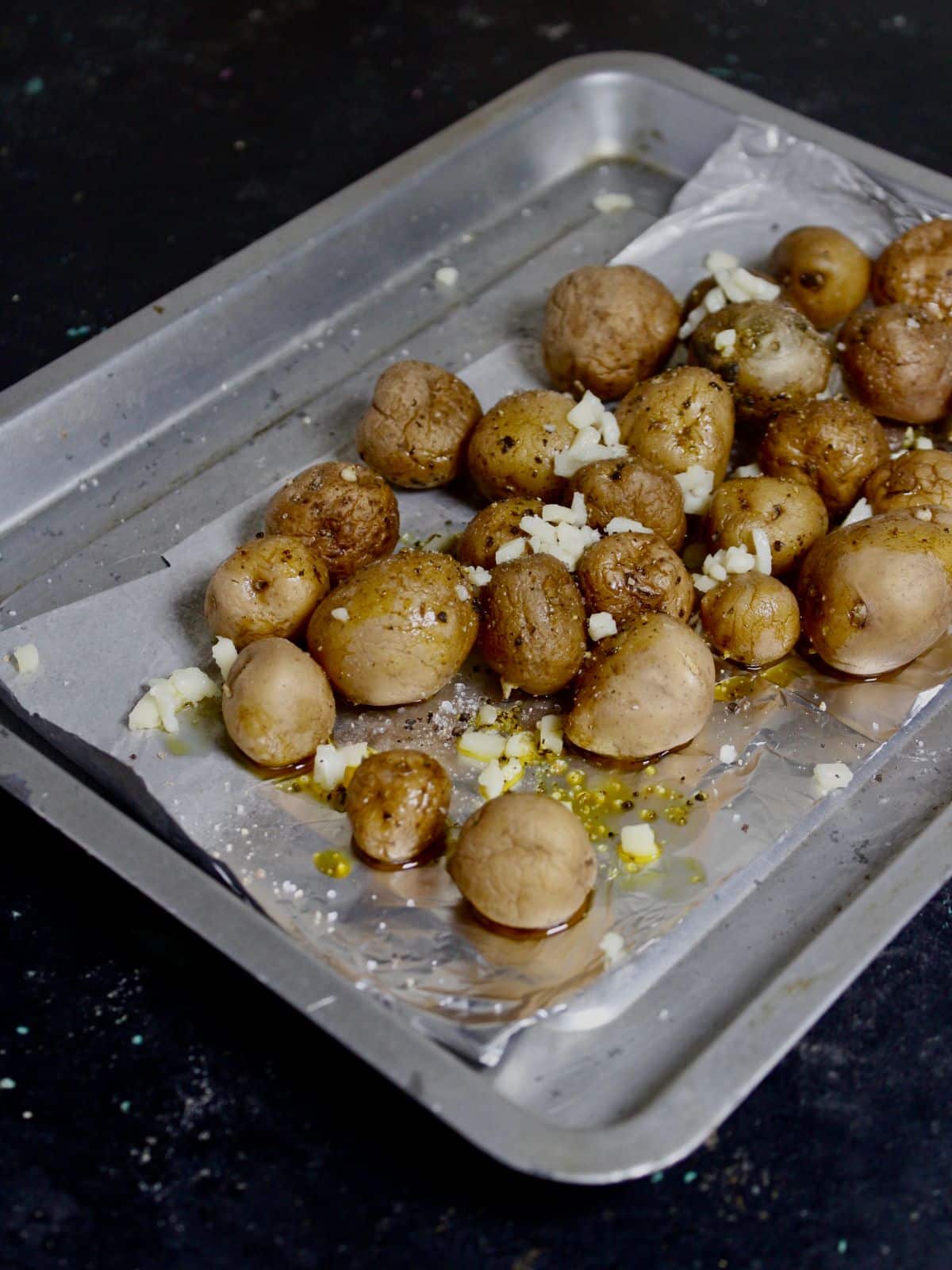 Take boiled potatoes on baking tray and sprinkle some oil with cheese on top 