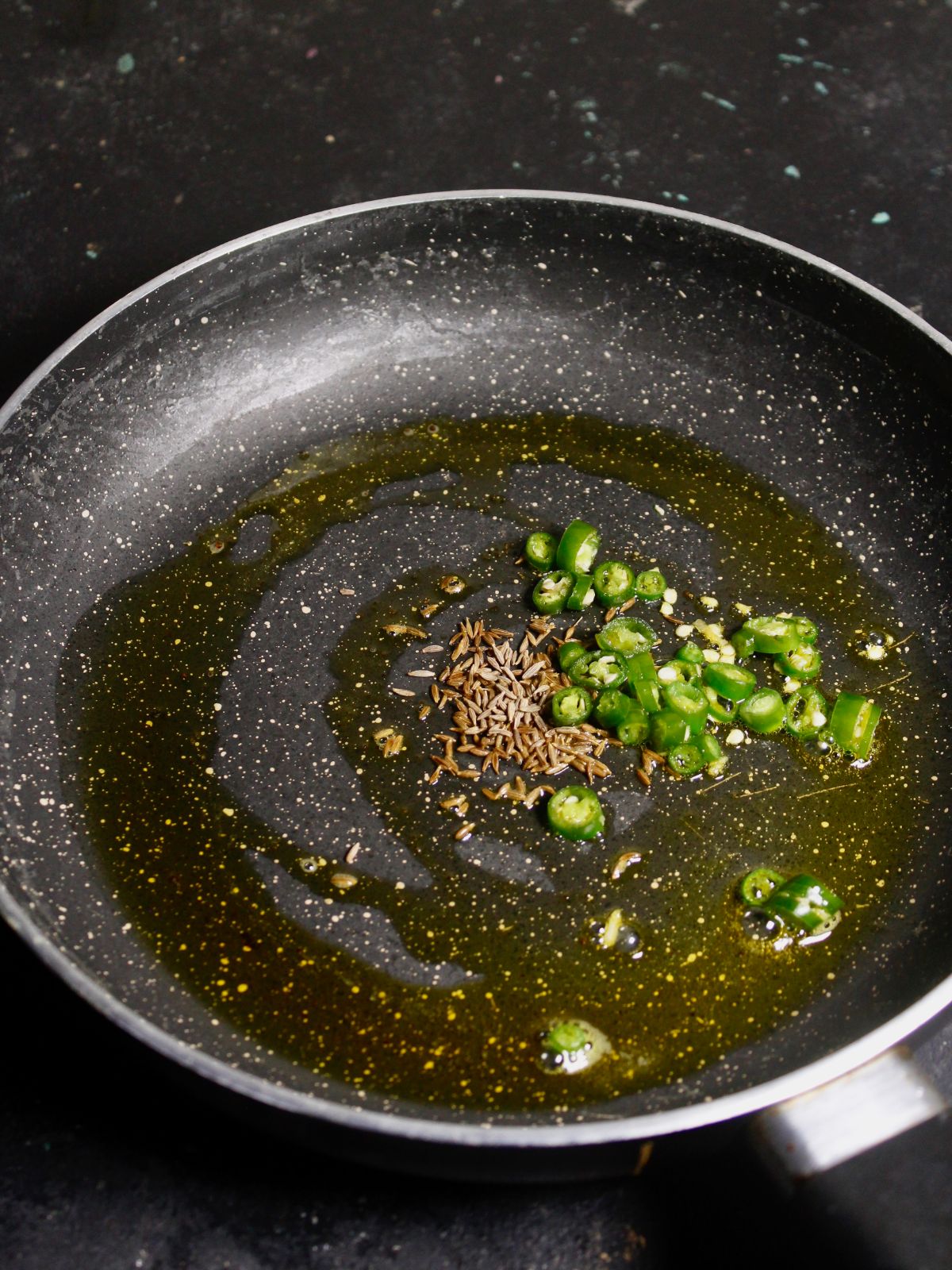 Add oil, green chilies and cumin seeds in a pan and saute 