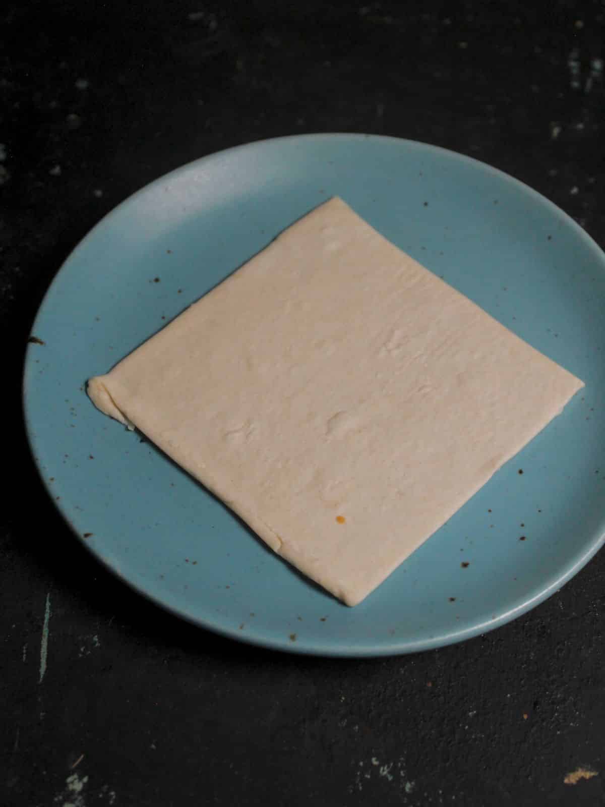 Take pastry square sheet on a plate 