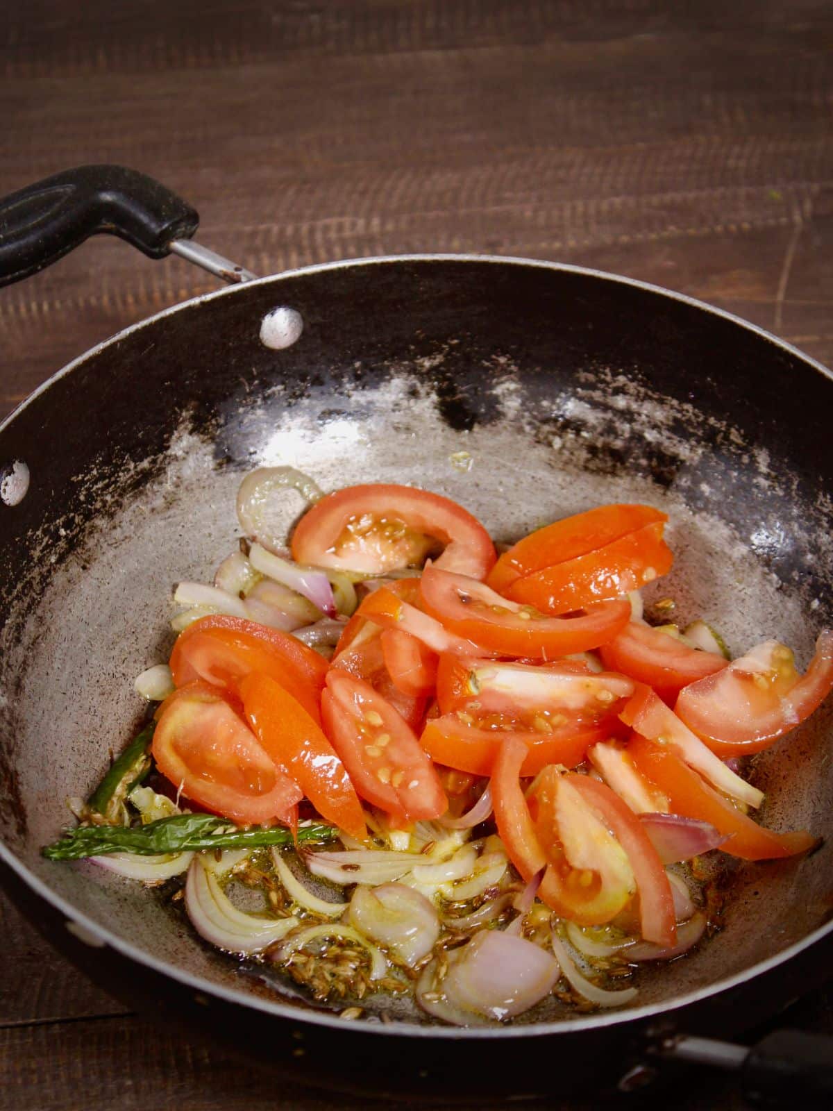 add chopped tomatoes and green chilies to the pan and saute 