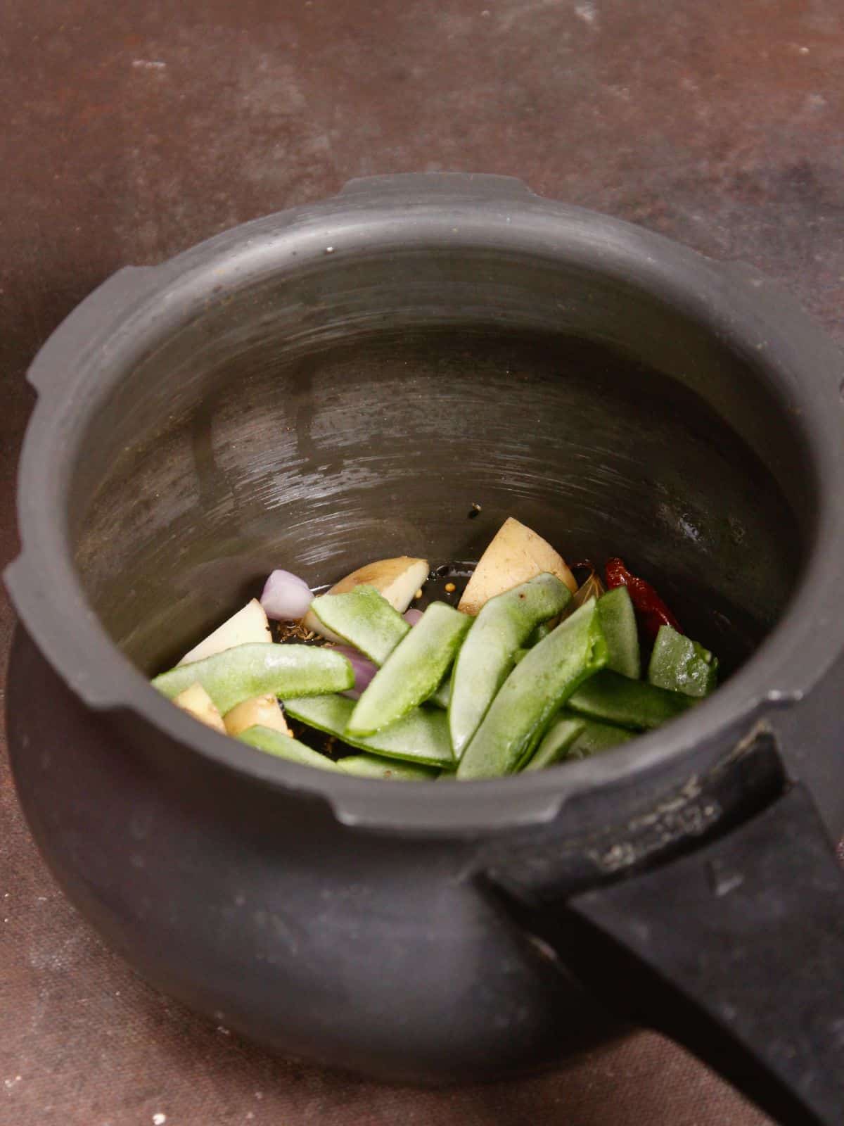 add chopped onions, broad beans and potatoes in the pressure cooker 