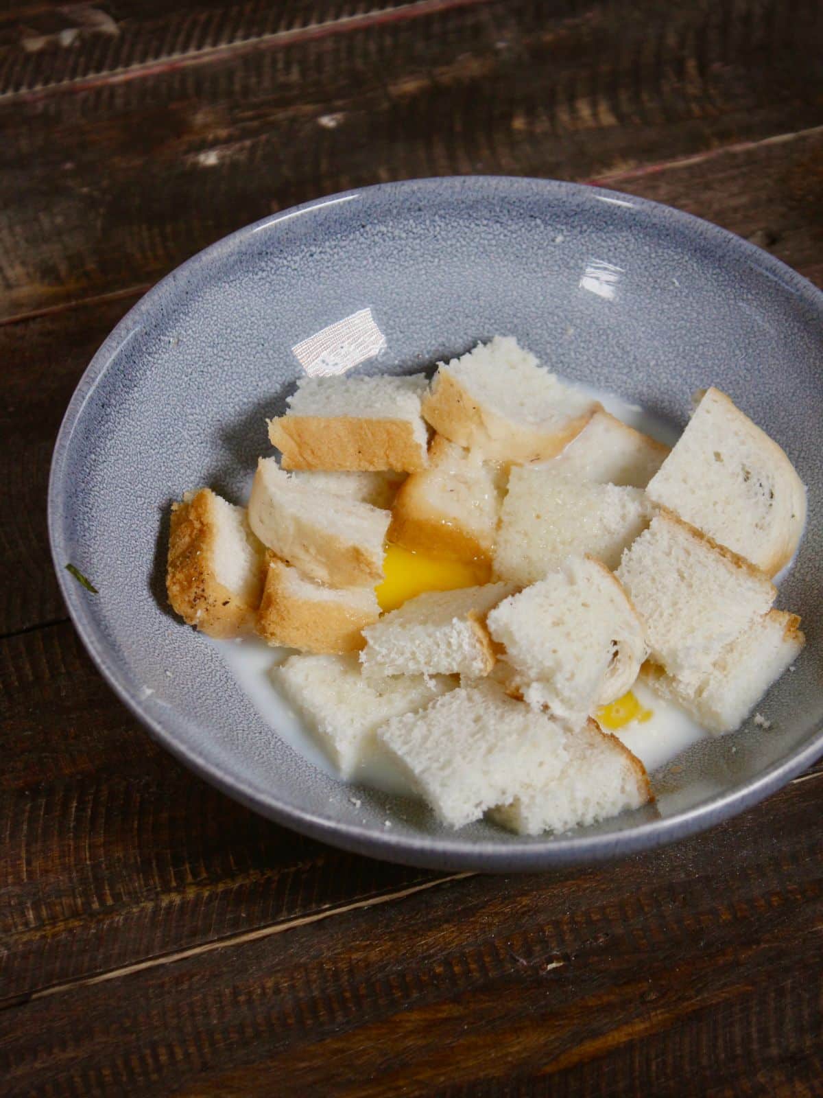 take eggs, milk, bread cubes in a bowl 