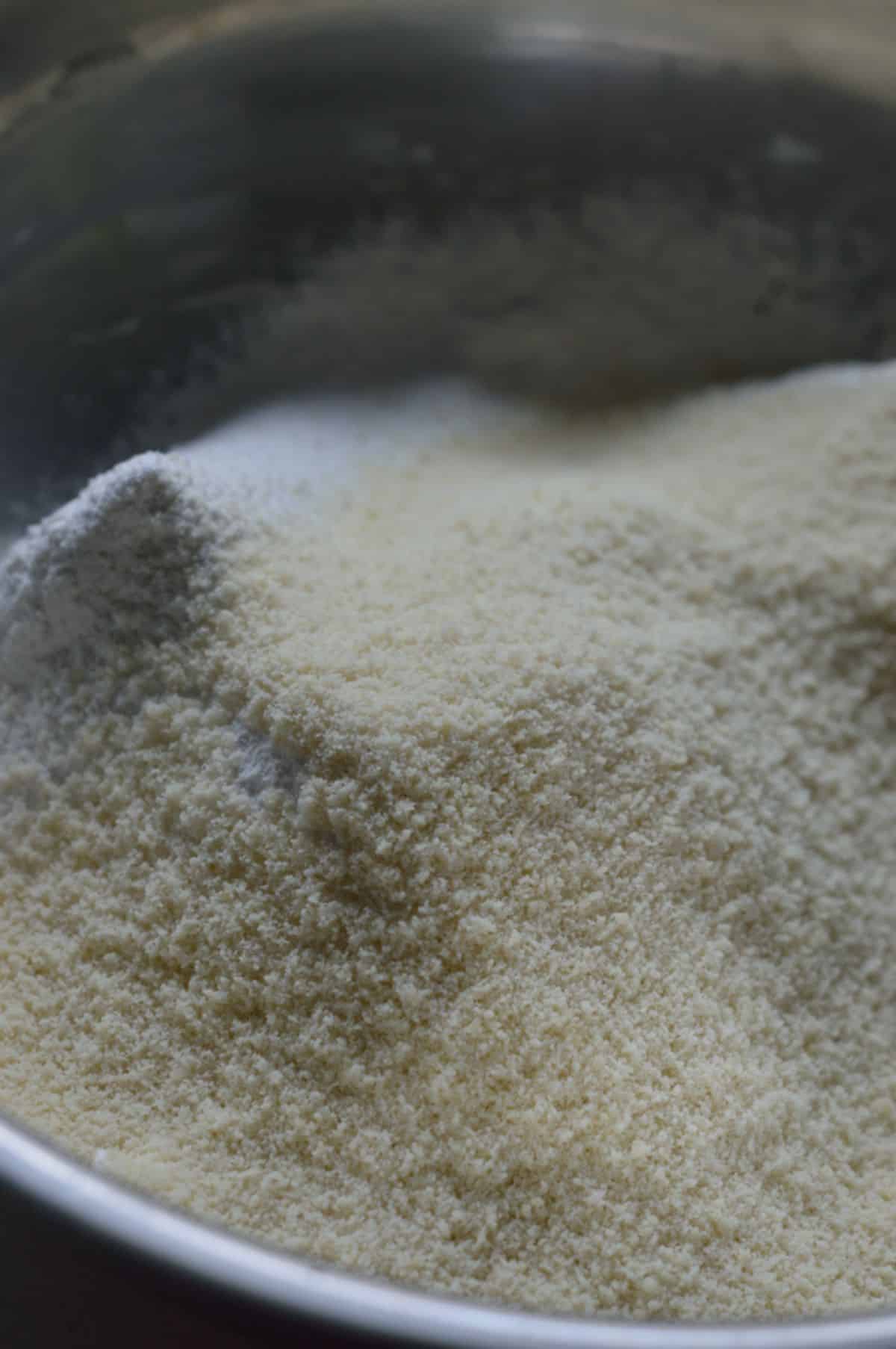 Almond flour, powdered sugar, baking powder, and cardamom powder in a bowl.