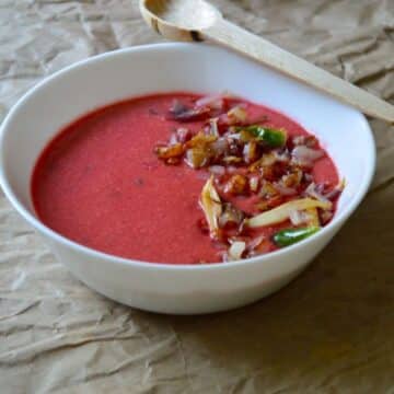 Beetroot Kadhi dish in a white bowl with a wooden spoon.