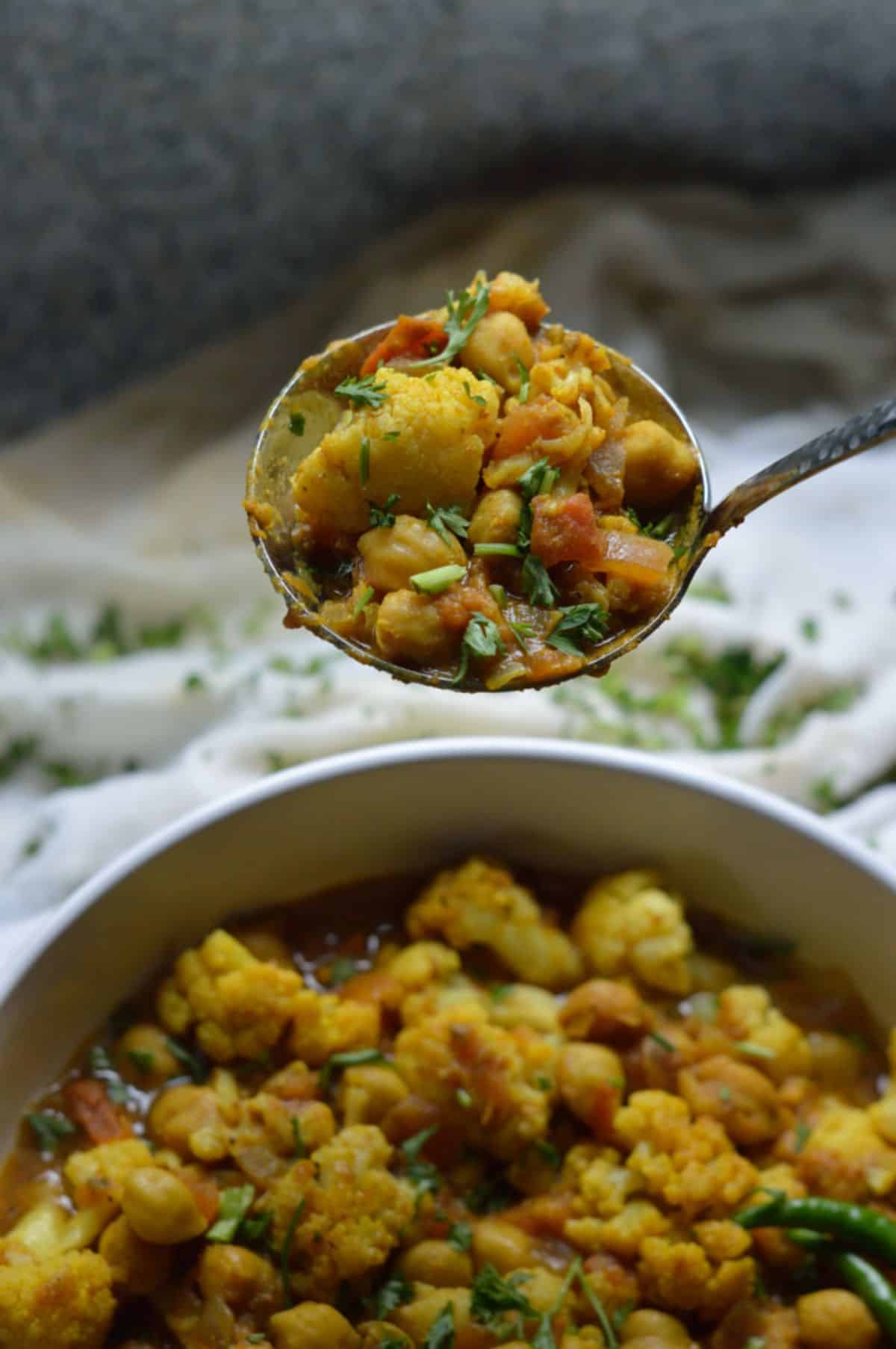Chana Gobi Masala dish in a white bowl and on a spoon.