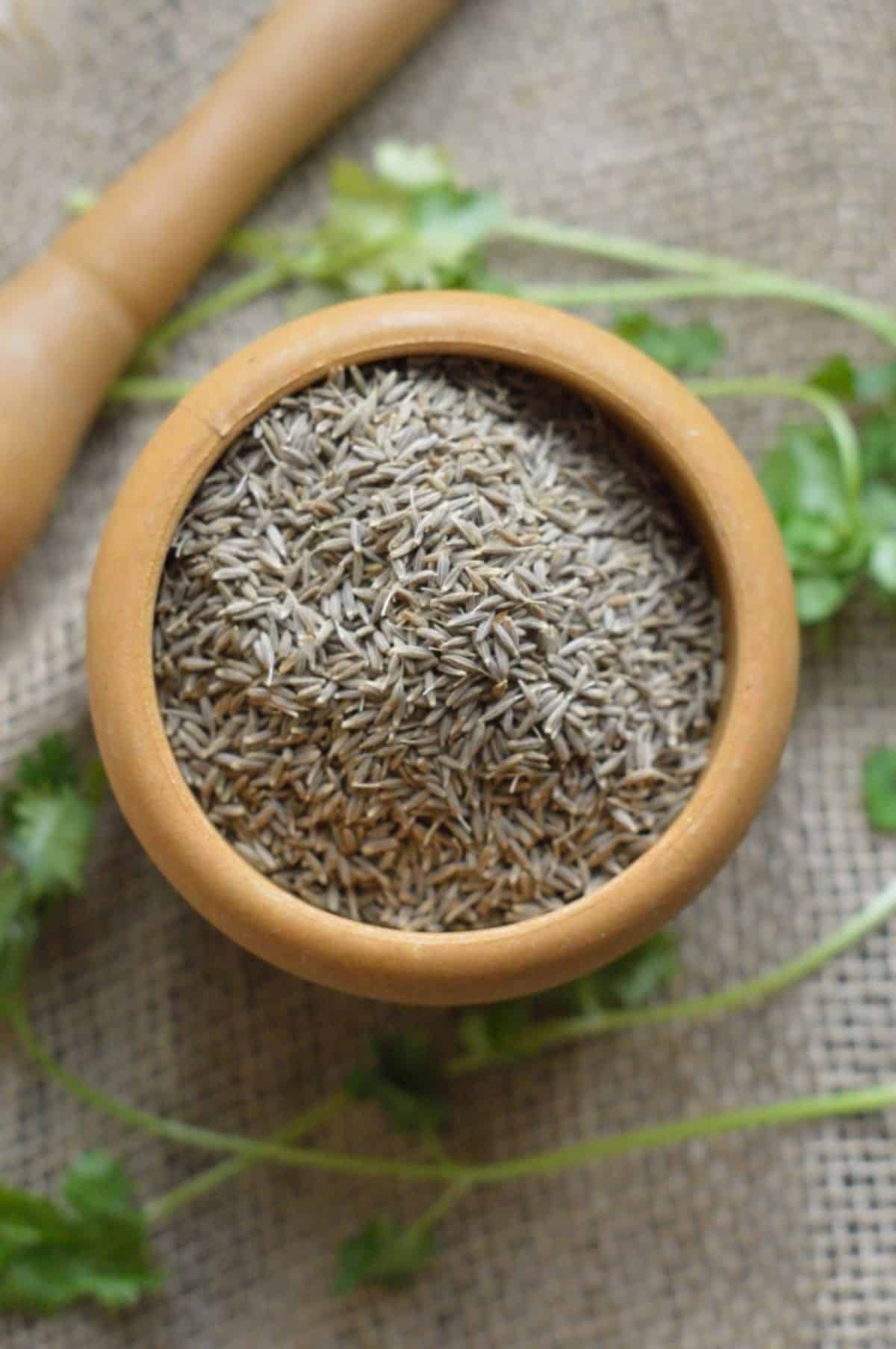 Dried cumin seeds in a brown bowl.