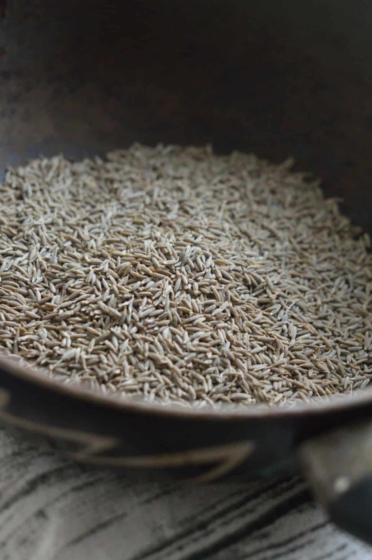 Roasted cumin seeds in a pan.