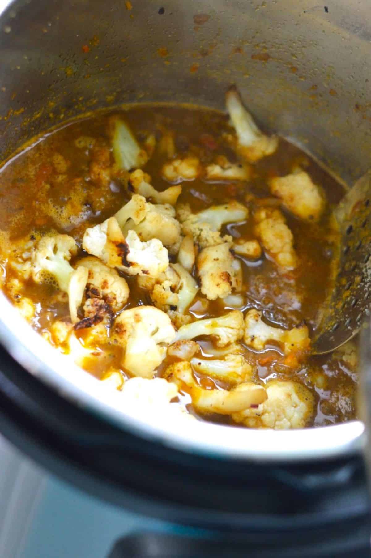 Adding chopped cauliflower in a pot.