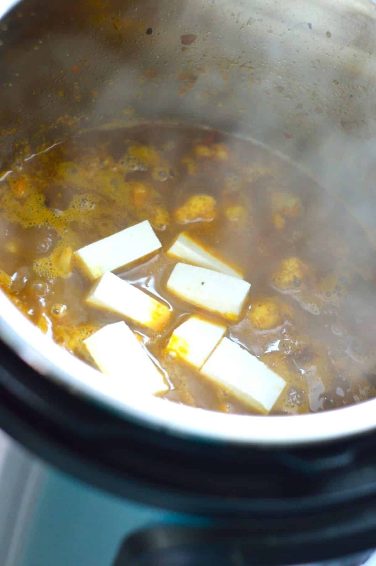 Adding paneer cubes in a pot.