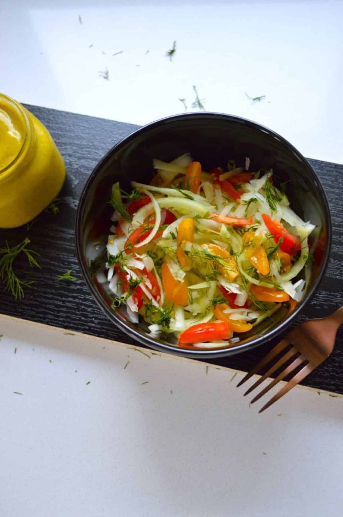 Vegan Green Papaya Salad in a black bowl on a wooden tray.