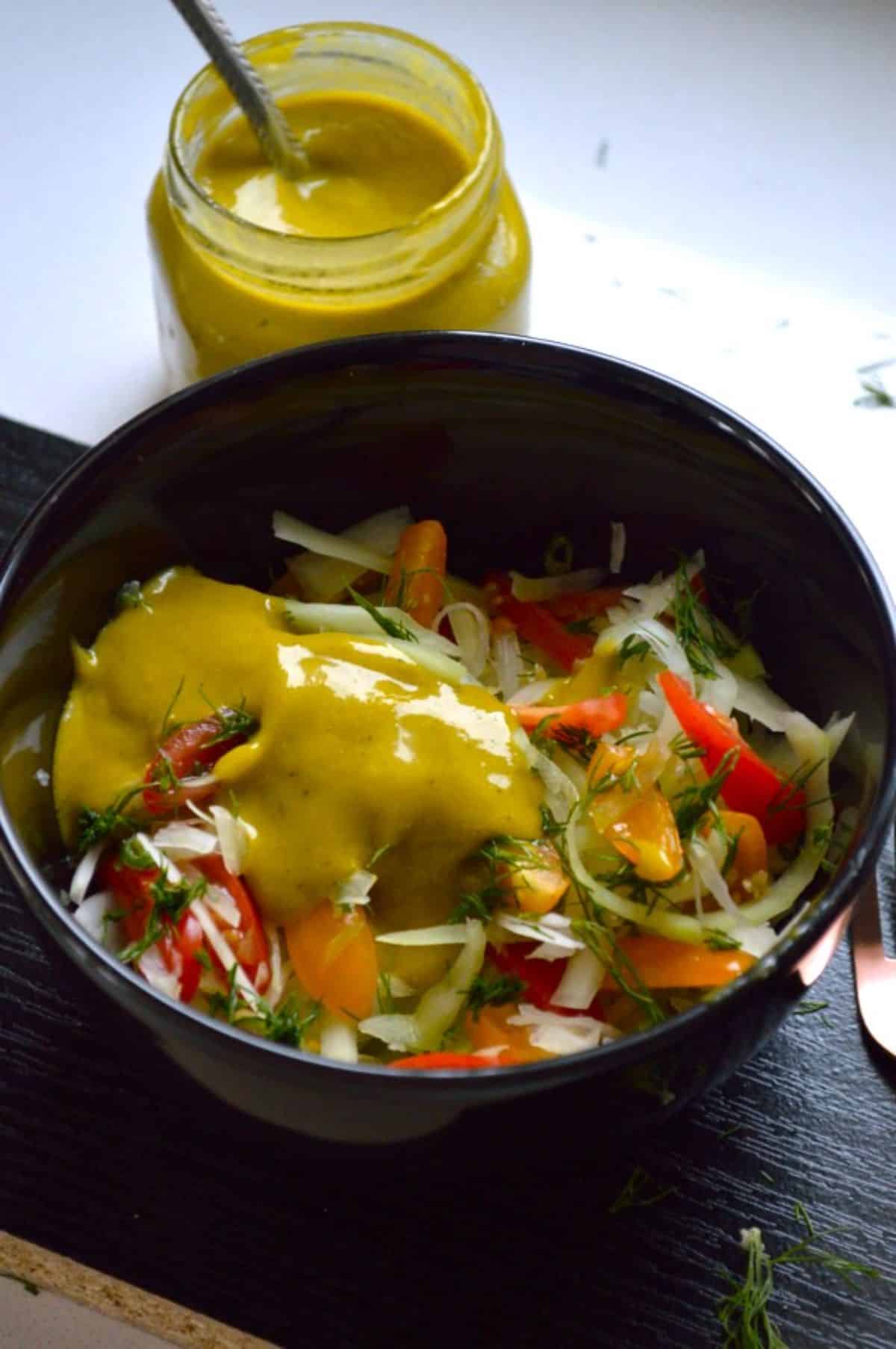 Vegan Green Papaya Salad in a black bowl drizzled with a spicy mango dressing.