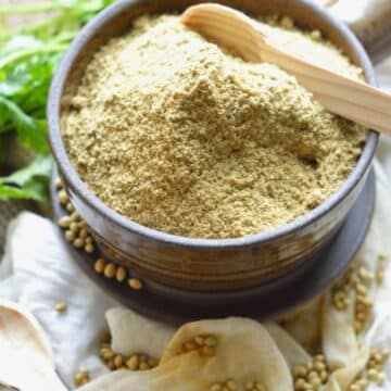 Coriander Powder in a brown bowl with a wooden spoon.