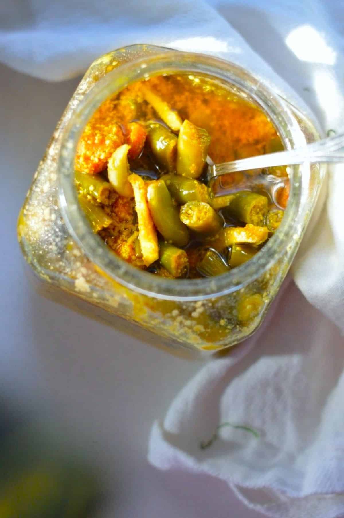 Indian Mixed Pickles in a glass jar with a spoon.