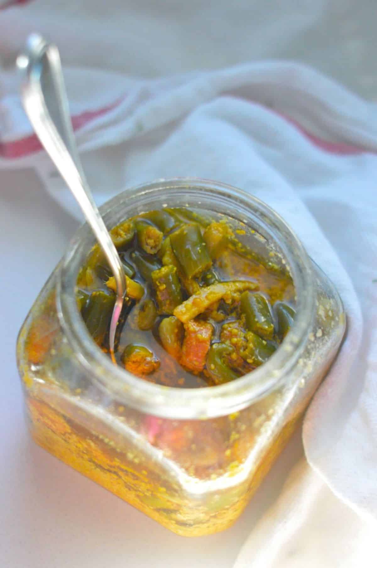 Indian Mixed Pickles in a glass jar with a spoon.