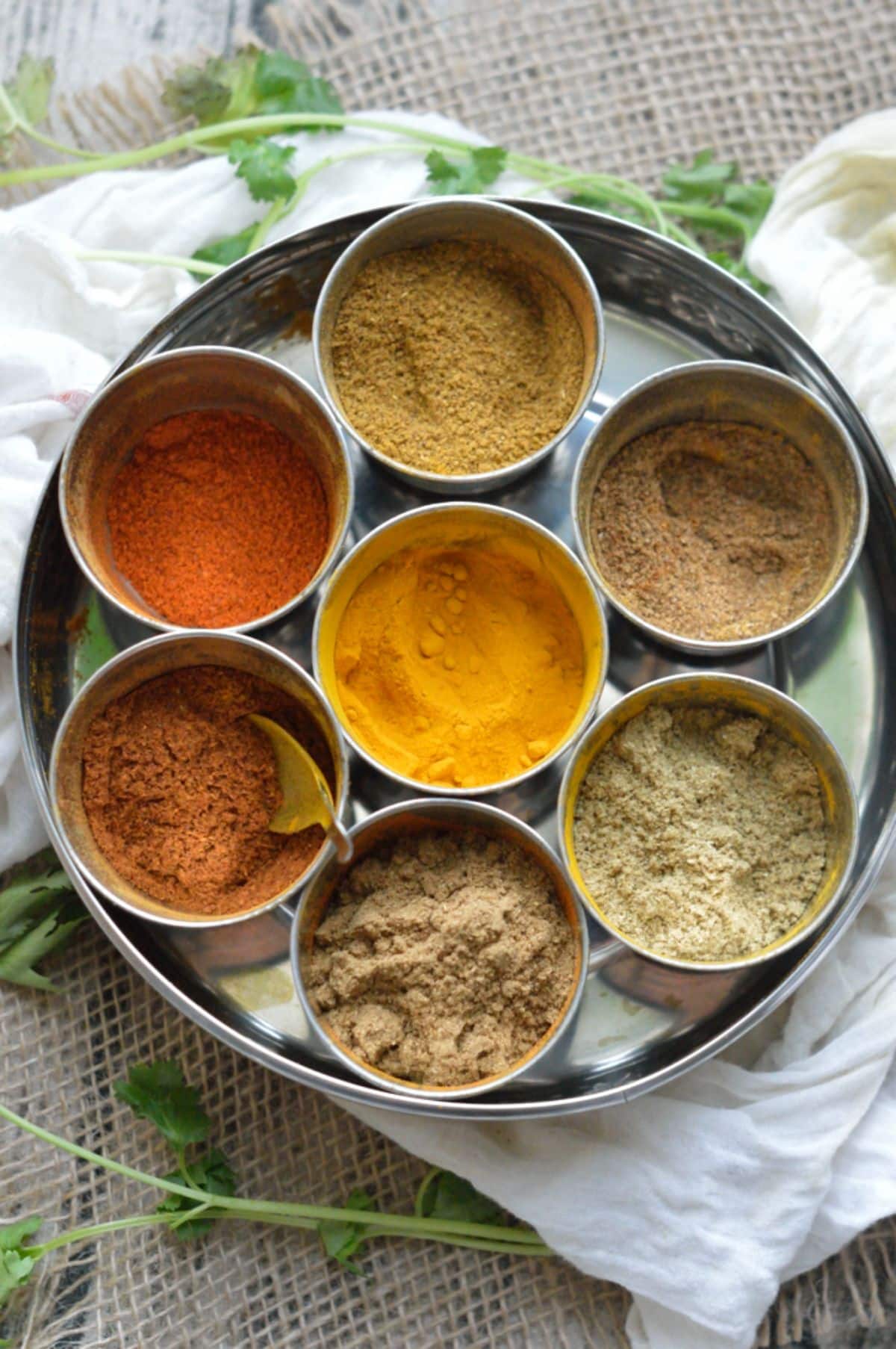 7 different spices in bowls on a tray.