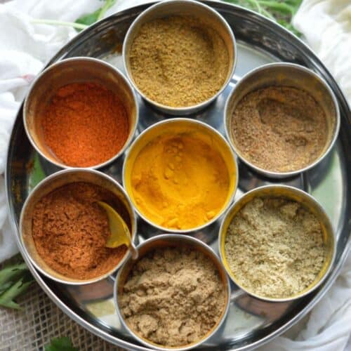 7 different spices in bowls on a tray.