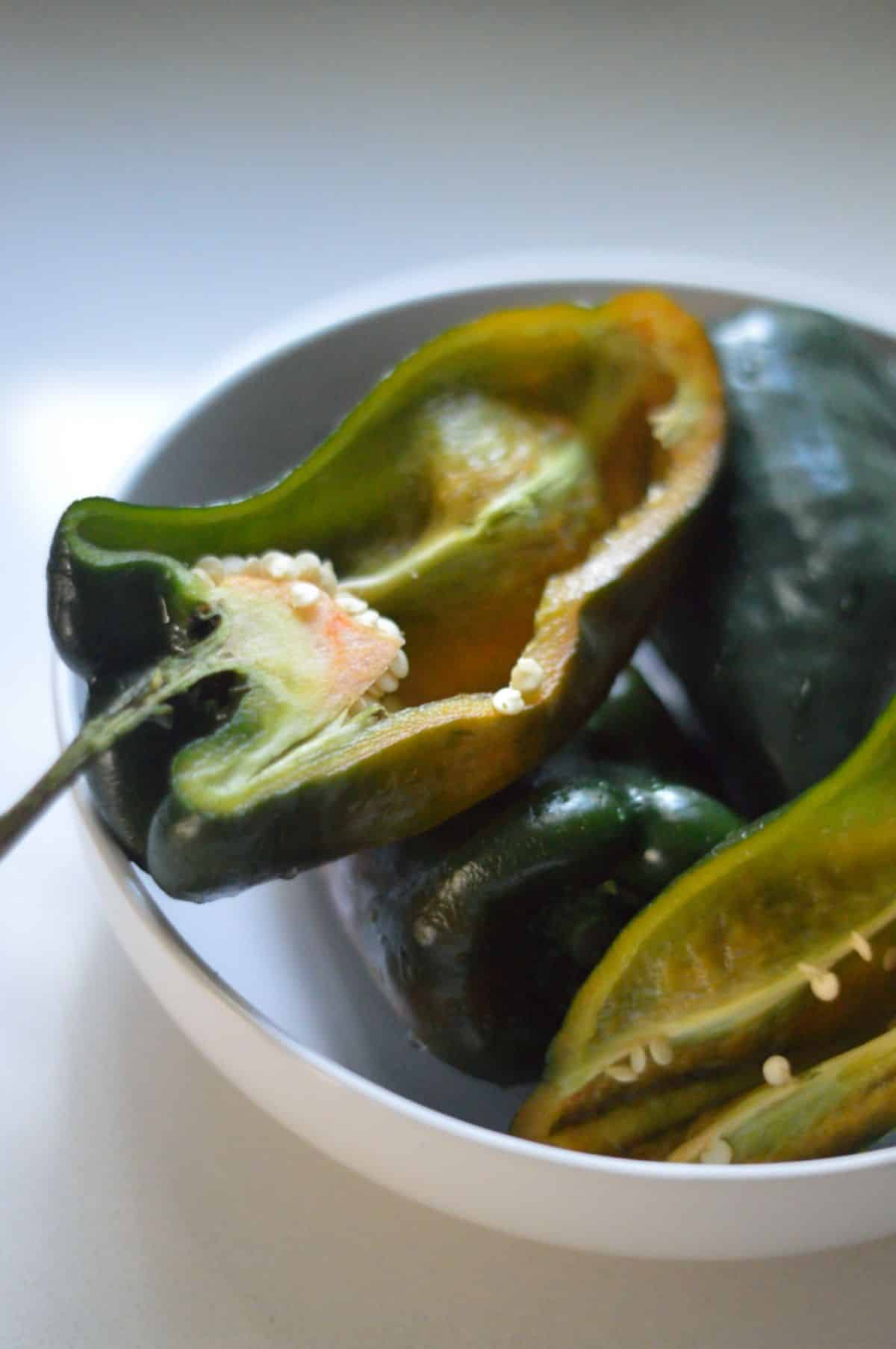 A white bowl full of green peppers.