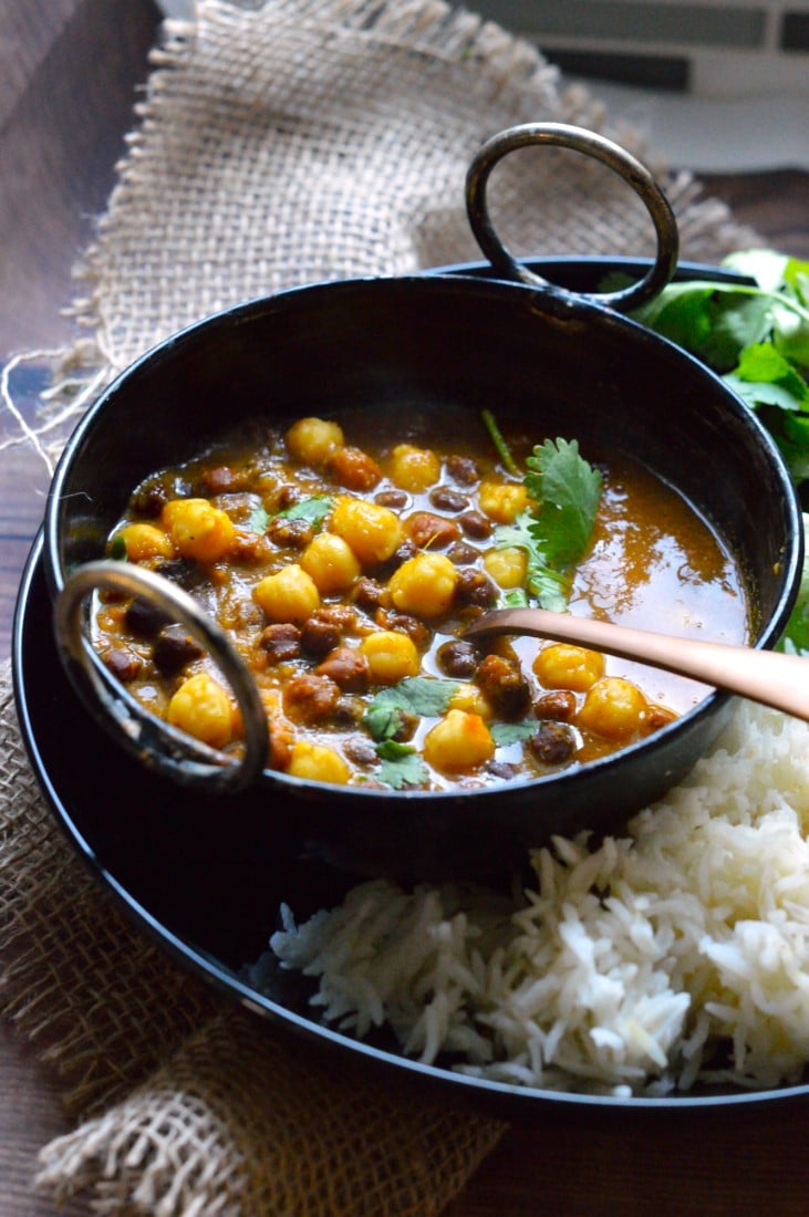 Mixed Chickpeas Curry in a black bowl with a spoon.