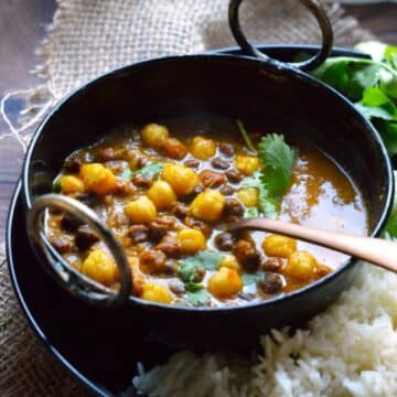 Mixed Chickpeas Curry in a black bowl with a spoon.