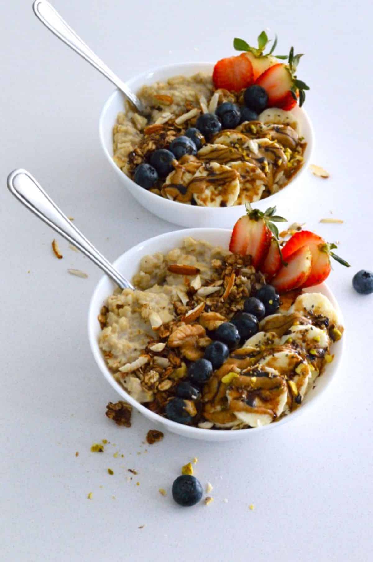 Pressure Cooker Oatmeal in white bowls with fruits on the top.