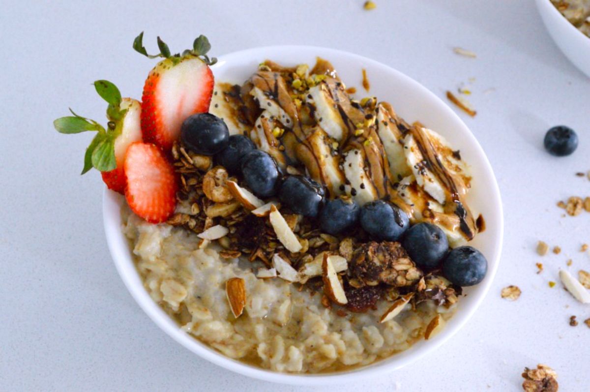 Pressure Cooker Oatmeal in a white bowl with fruits on the top.