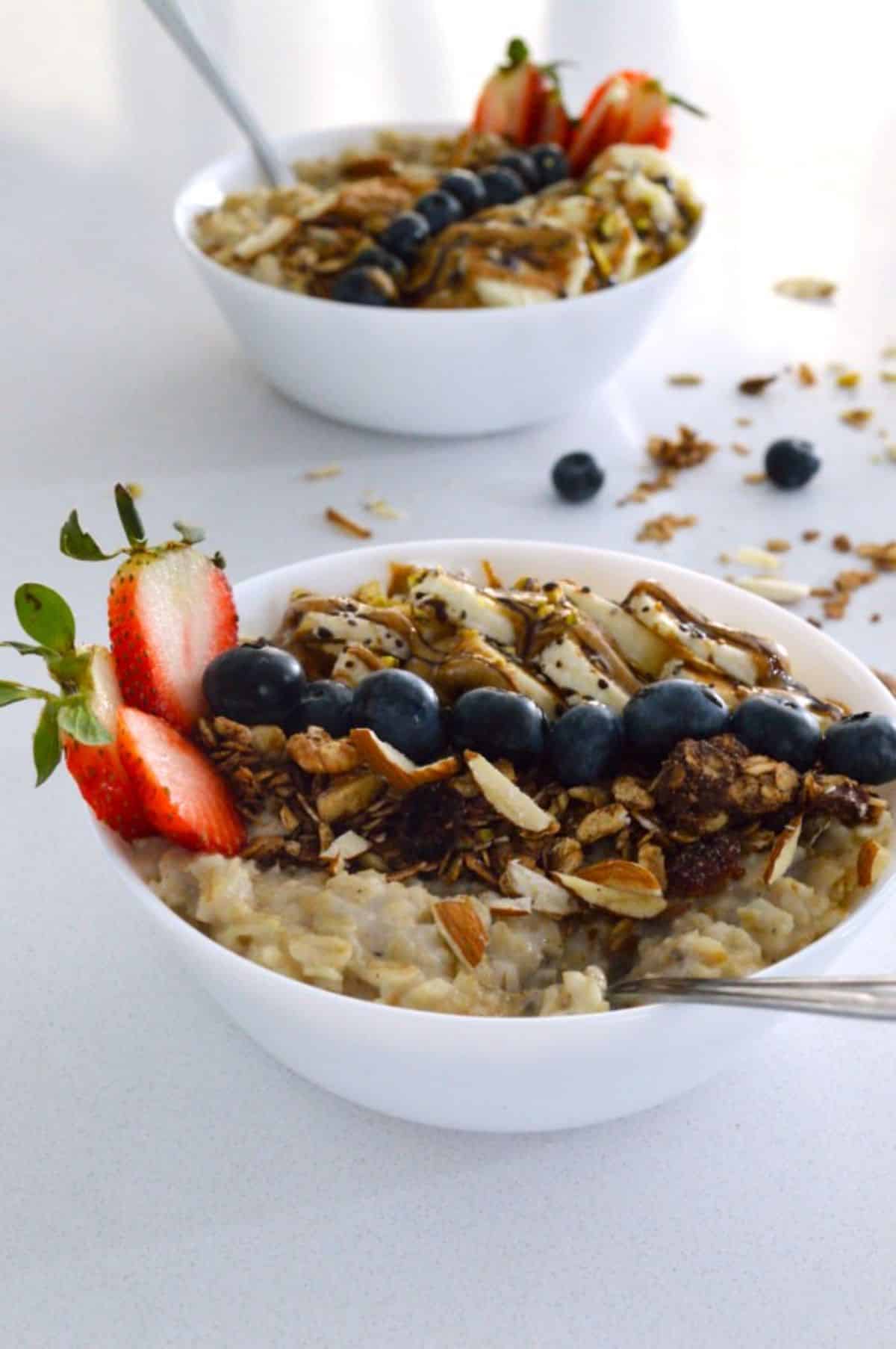 Pressure Cooker Oatmeal in white bowls with fruits on the top.