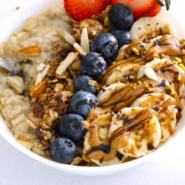 Pressure Cooker Oatmeal in a white bowl with fruits on the top.