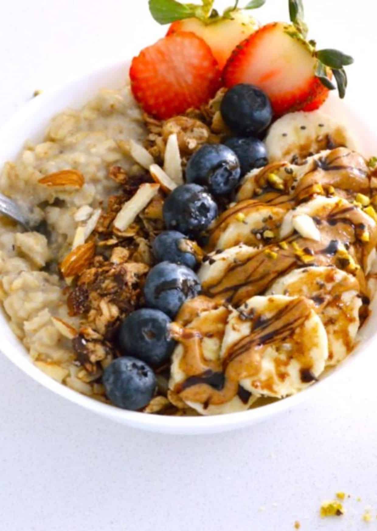Pressure Cooker Oatmeal in a white bowl with fruits on the top.